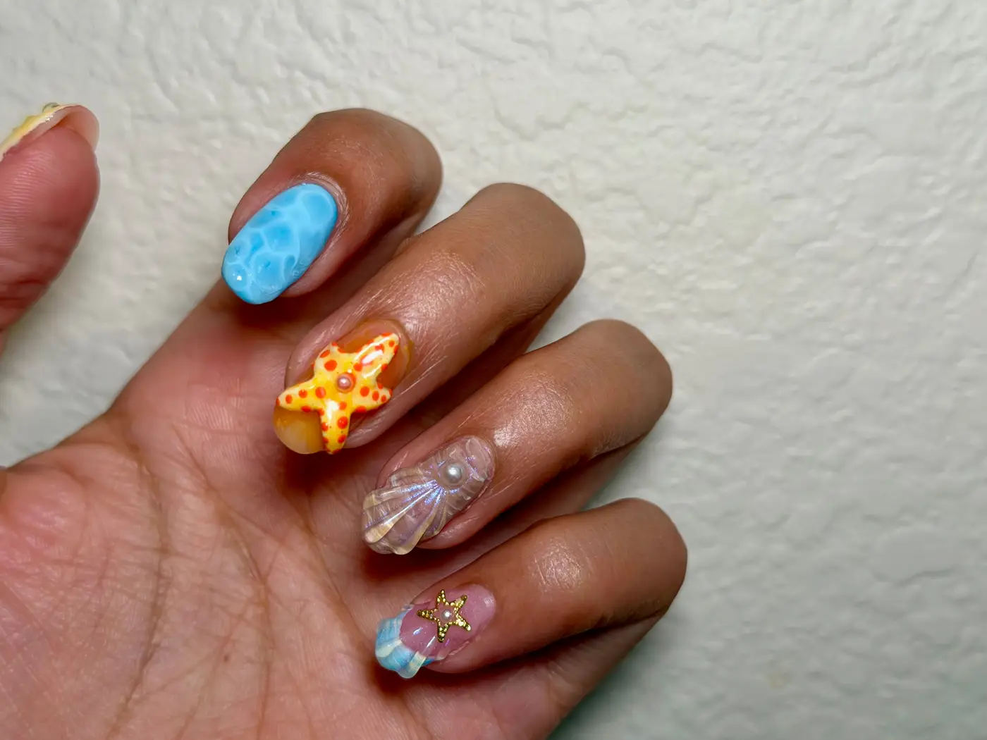 Almond set painted like the ocean, with a 3D starfish, a shell, and blue water marbling